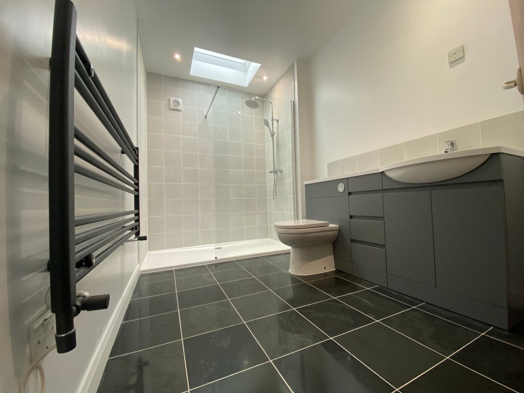 grey bathroom with accessible shower, vanity unity, designer towel rail